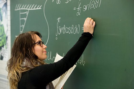 Eine Studentin schreibt Formeln an eine Tafel. Foto: Daniel Karmann