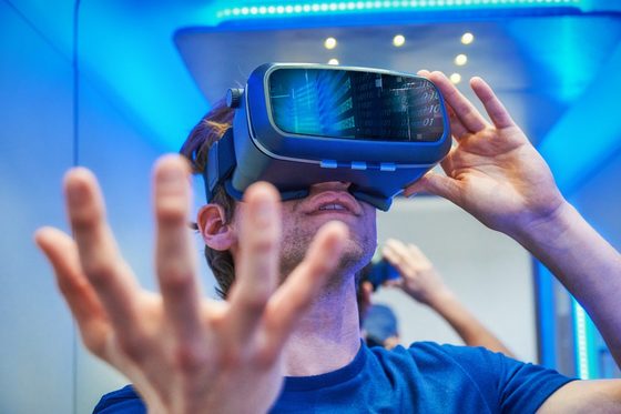 Ein junger Mann sieht durch eine VR-Brille.