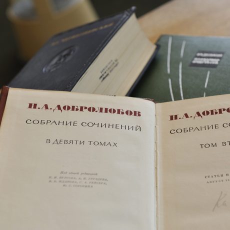 Ein Buch mit russischer Schrift liegt aufgeklappt auf zwei weiteren dicken Büchern.