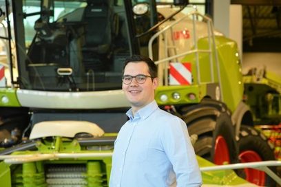 Ein Ingenieur für Agrartechnik steht vor einem grünen Mähdrescher