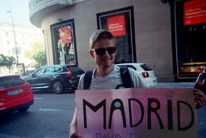 Blogger David mit einem Pappschild, auf dem MADRID steht.