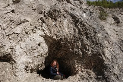 Eine junge Frau sitzt in einer Felsöffnung.