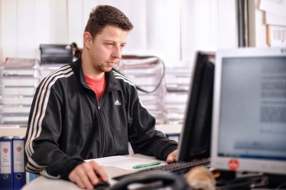 Junger Mann, sportlich gekleidet, sitzt vor dem PC