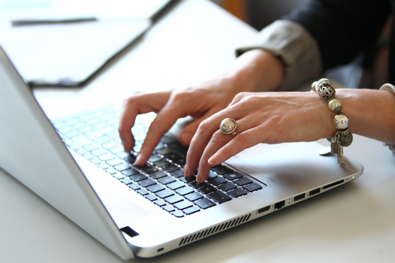 Eine Frau tippt etwas auf der Tastatur eines Laptops.