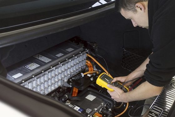 Ein KFZ-Mechatroniker der Fachrichtung System- und Hochvolttechnik arbeitet an einem Fahrzeug.
