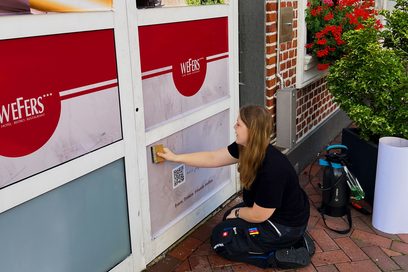 Lilly Vedler bei der Arbeit mit einem Schild an einer Fensterfront