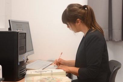 Eine junge Frau sitzt am Schreibtisch vorm PC.