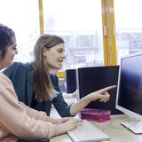 Eine junge Frau zeigt einer anderen jungen Frau etwas am Computer. (Foto: Bundesagentur für Arbeit)