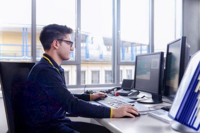 Junger Mann sitzt am Schreibtisch und arbeitet am Computer. (Foto: Julien Fertl)