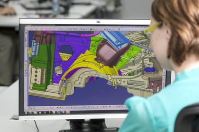 Eine Frau arbeitet an einem Computerarbeitsplatz mit einem CAD-Programm an einem Autoteil.