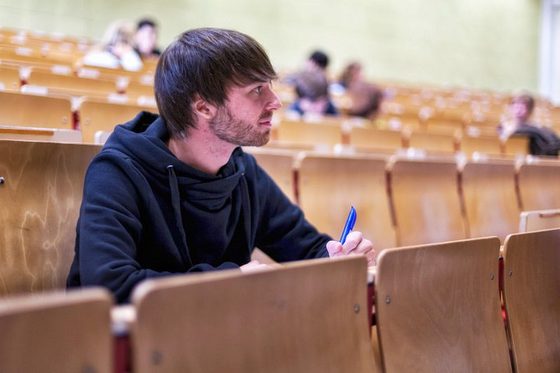 Student sitzt in einem Hörsaal und verfolgt eine Vorlesung