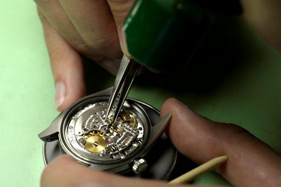 Mit feinem Werkzeug reparariert ein Uhrmacher eine Armbanduhr.