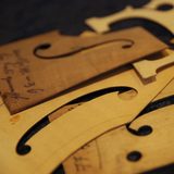 Dünne Holzplatten mit Bleistiftaufschrift in der Form von Details eines Saiteninstruments liegen aufeinander. (Foto: Meramo Studios)