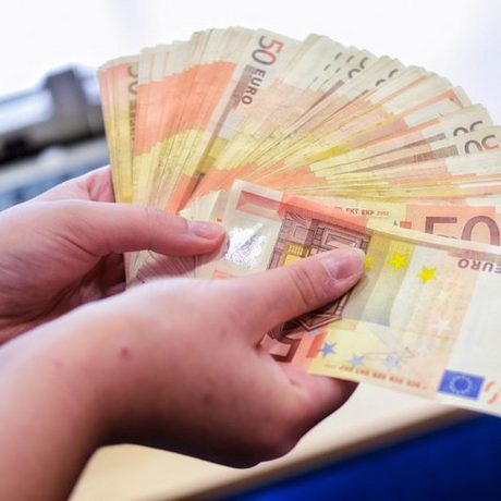 Zwei Hände die ein Bündel 50 Euro Scheine auffächern