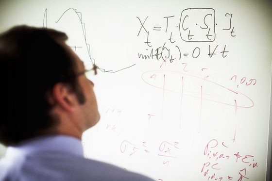Mann steht vor einer Flipchart mit mathematischen Formeln