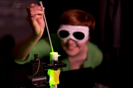 Eine Physiklaborantin mit Schutzbrille führt ein physikalisches Experiment durch. Foto: Axel Jusseit