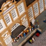 Blick von oben auf ein Miniatur-Modell eines Universitätsgebäudes mit Miniatur-Figuren am Eingang und auf der Treppe.