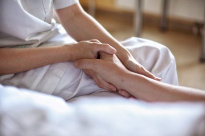 Eine Krankenschwester hält die Hand einer Kranken auf der Palliativstation. Foto: Axel Jusseit