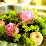Nahaufnahme eine Biedermeier-Blumenstraußes mit rosafarbenen Rosen; hellgelben Ranunkeln und grünen Pflanzenteilen.