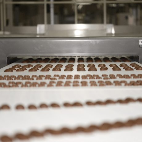 Viele Schokoladenstücke in unterschiedlichen Formen laufen über ein Fließband.
