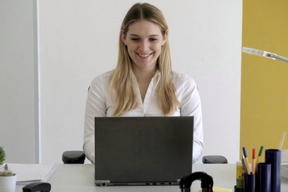 Eine Frau sitzt am Schreibtisch vor einem Laptop.