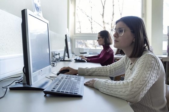 Zwei junge Frauen sitzen an Computern und arbeiten.