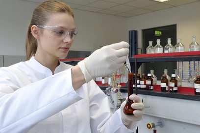 	Eine junge Frau füllt im Labor mit einer Pipette eine Flüssigkeit in ein Reagenzglas.