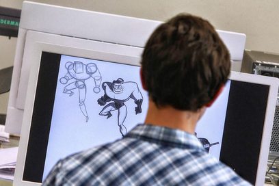 Ein junger Mann arbeitet am Computer an der Visualisierung von zwei Computerspiel-Figuren mit einem 3D-Programm. (Foto: Karl-Josef Hildenbrand)