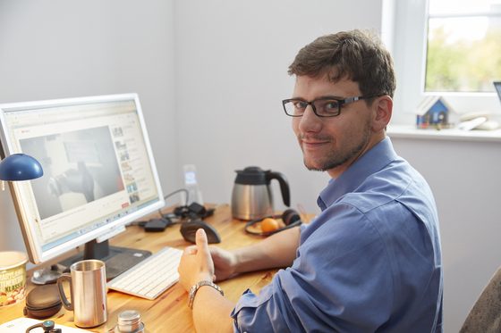 Ein Mann sitzt in einem Büro am Schreibtisch und arbeitet mit dem Computer.