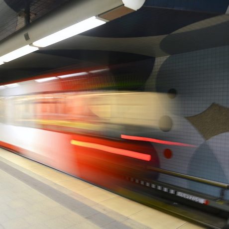 Bild eines verlassenen Bahnsteigs in einer U-Bahn-Station. Auf dem Bahngleis fährt eine U-Bahn weg. Durch die Bewegung wird er auf dem Bild unscharf.