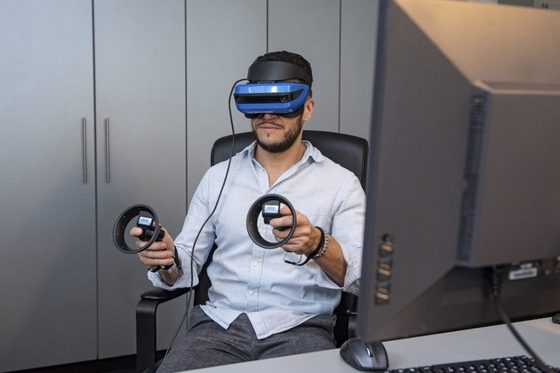 Ein Mann hat eine VR Brille auf und Joysticks in den Händen.