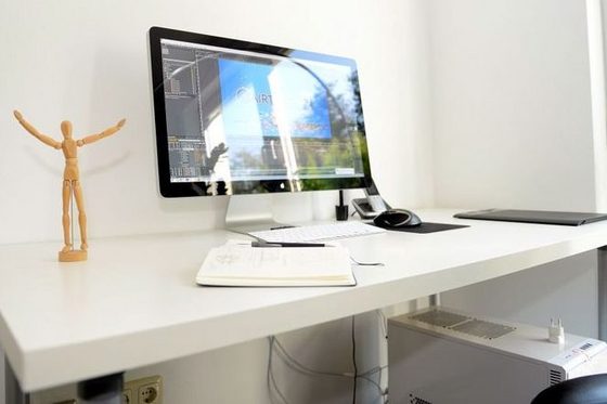 Ordentlicher Schreibtisch mit Bildschirm und Holzpuppe. (Foto: Nadine Zwingel)