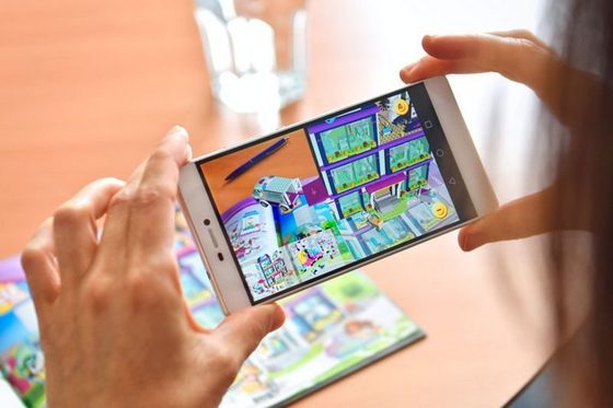Frau hält Smartphone über Spielzeugproduktkatalog und lässt sich durch eine Augmented Reality-App die Spielsachen in 3D anzeigen. (Foto: Martin Rehm)