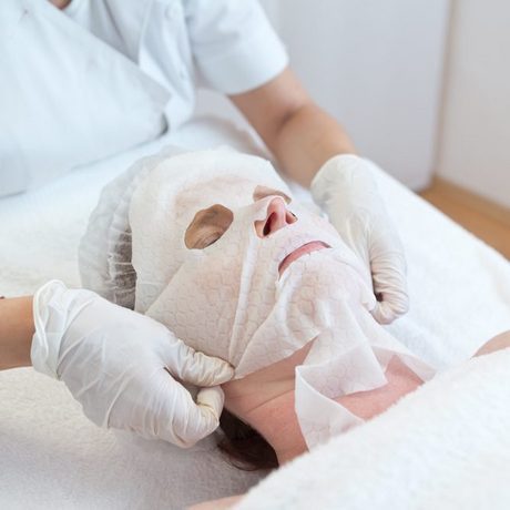 Detail: Kosmetikermeisterin bei der Behandlung einer Kundin mit Gesichtsmaske.