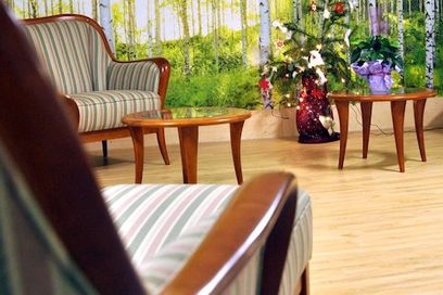 Blick in einen Raum mit gepolsterten Sesseln und hellem Holzboden.