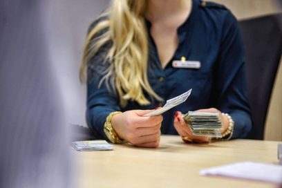 EineFrau sitzt im Stuhl und hält Geldscheine in der Hand (Foto: Martin Rehm)