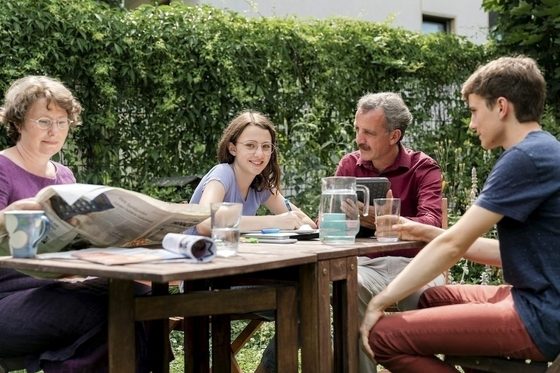 Eine Familie sitzt gemeinsam im Garten an einem Tisch.
