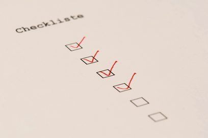 Detailaufnahme einer Checkliste mit sechs schwarzen Kästchen untereinander. Die vier oberen Kästchen wurden mit einem roten Stift angehakt. 