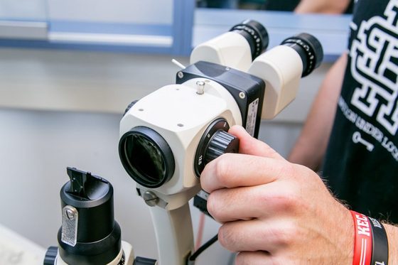 Ein Mann bedient ein Geräte zur Untersuchung von Augen. Es ist nur seine Hand zu sehen.