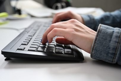 Eine junge Frau tippt auf einer Computer-Tastatur.