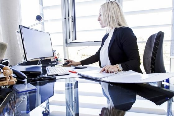 Eine Betriebswirtin sitzt in einem Büro am Schreibtisch und arbeitet am Computer.