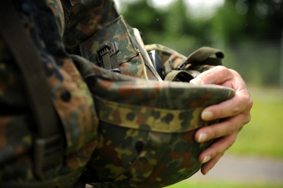 Ein Soldat hält seinen Stahlhelm in der Hand.