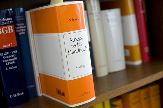 Gesetzbücher in einem Regal, ein Buch über Arbeitsrecht ist herausgezogen.
