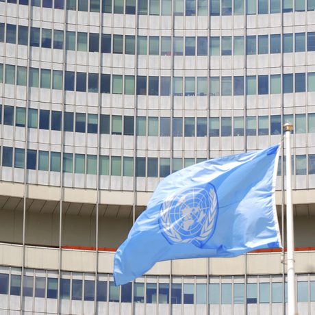 UNO-Gebäude mit wehender UNO-Fahne in weiß-hellblau davor.