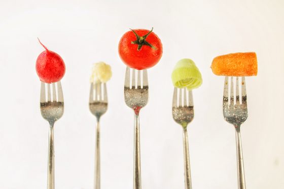 Das Foto zeigt fünf stehende Gabeln, auf denen Lebensmittel aufgespießt sind: Radieschen, Blumenkohl, Tomate, Lauch und Möhre.