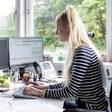 Eine junge Frau im Büro bearbeitet einen Vorgang am Computer.