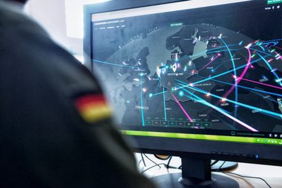 Mann in Uniform sitzt vor Rechner und analysiert Cyberattacken