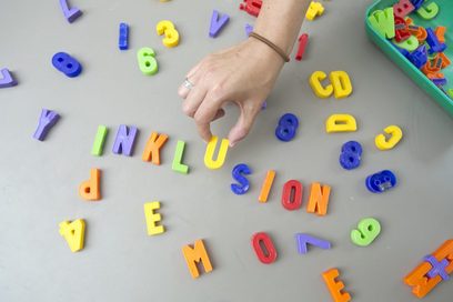 Eine Hand legt das Wort "Inklusion" aus bunten Magnetbuchstaben.