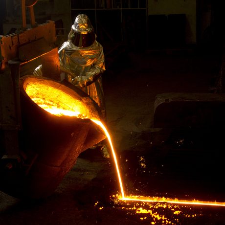 Junger Mann mit Schutzanzug giesst fluessiges Metall in eine Gussform. (Foto: Johannes Simon)