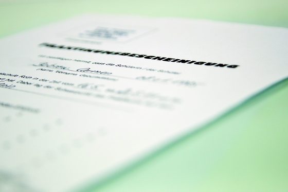 Ein Dokument mit der Aufschrift "Praktikumsbescheinigung" liegt auf einer weißen Fläche.